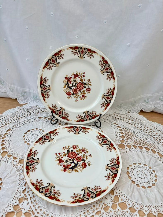 Two decorative plates with floral patterns on a lace tablecloth.