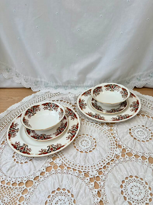 Set of ceramic dishes with floral patterns on a lace tablecloth.