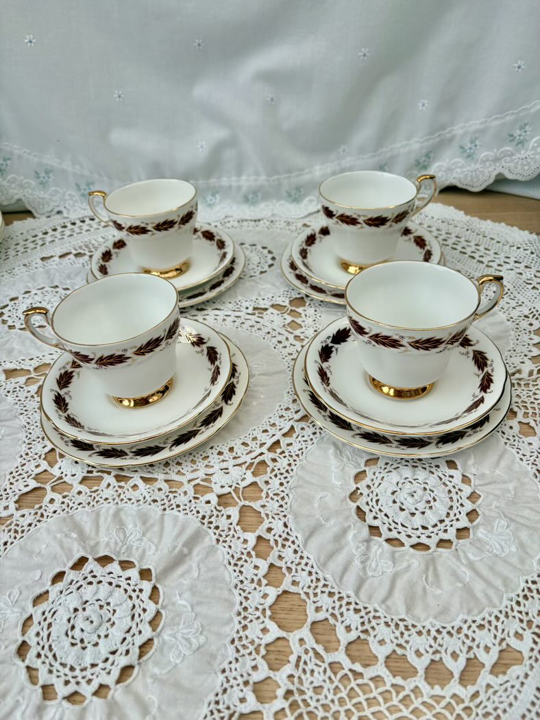 Set of four vintage-style tea cups and saucers on a lace tablecloth.