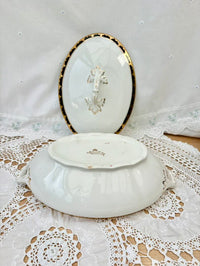 White ceramic dish with gold rim and cross design on a lace tablecloth.