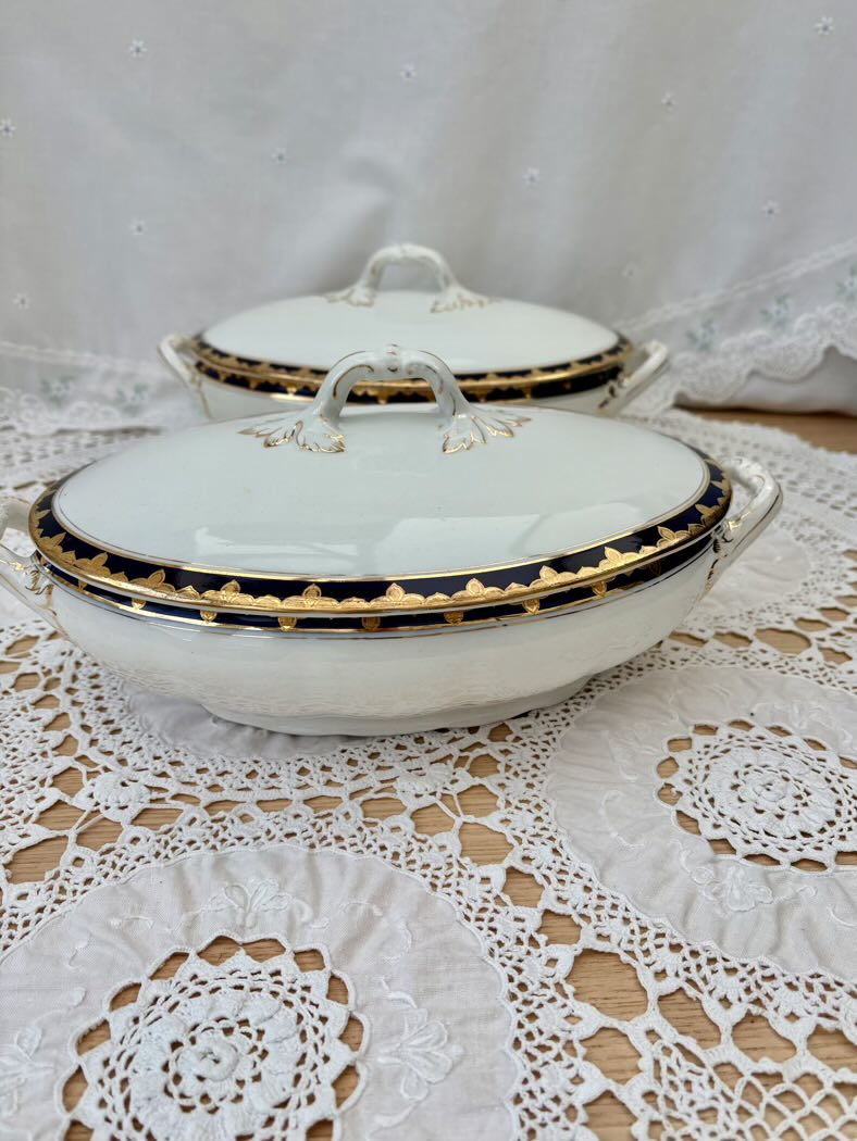 White ceramic tureen with gold trim on a lace tablecloth