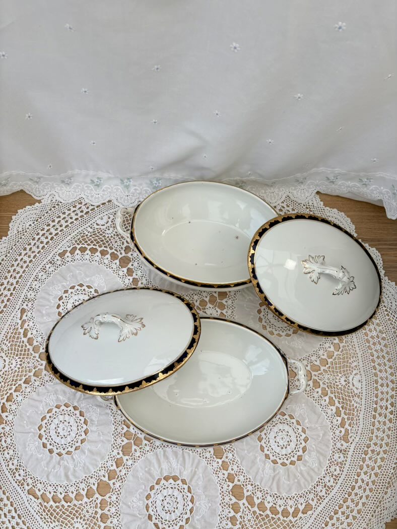 Set of two white ceramic plates with gold trim on a lace tablecloth.