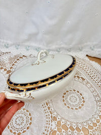 Decorative white dish with gold trim held over a lace tablecloth