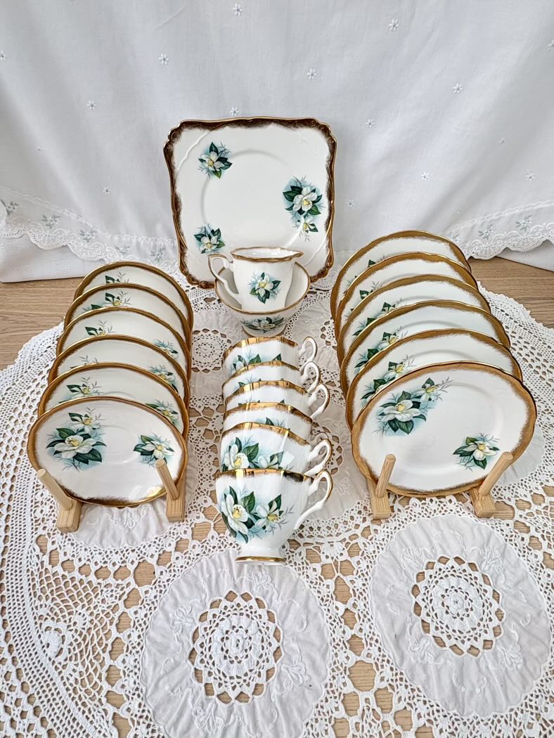 Vintage-style ceramic tea set with floral patterns on a lace tablecloth.