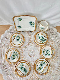 Set of decorative ceramic plates with floral patterns on a lace tablecloth.