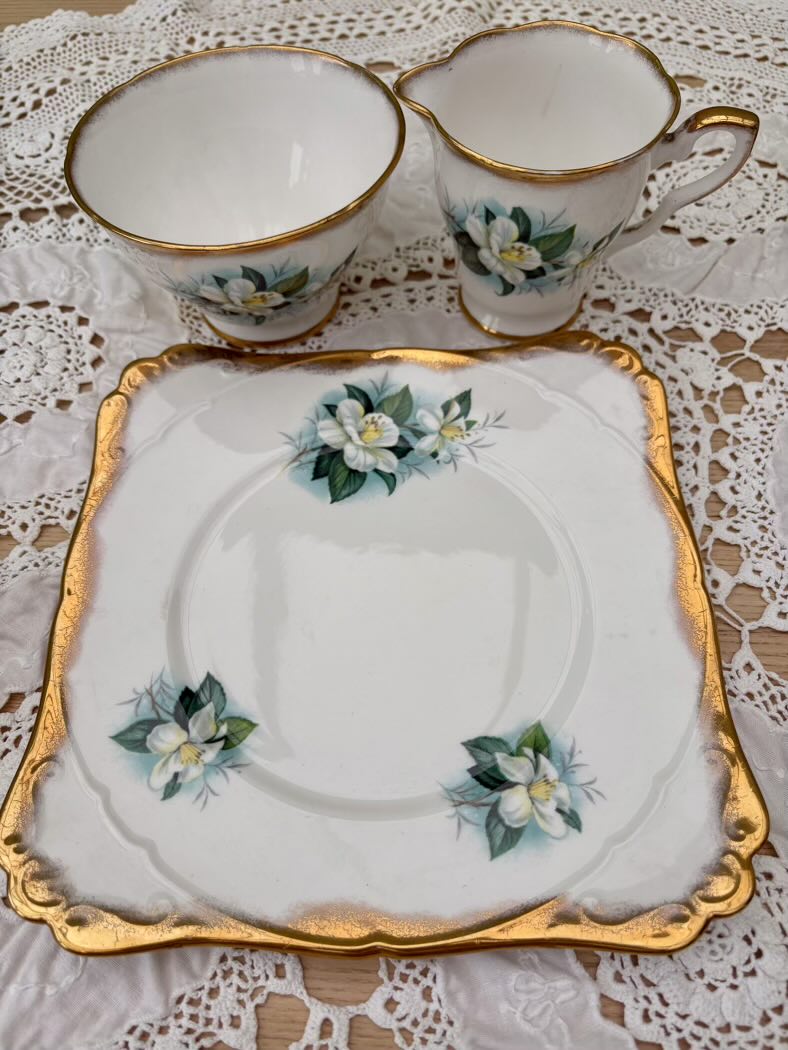 Set of floral teacup, saucer, and plate on a lace tablecloth