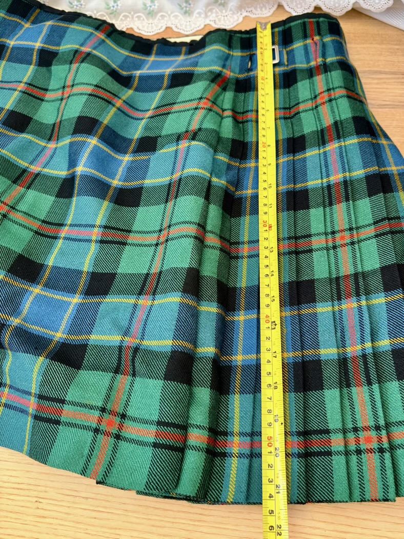 Green plaid fabric with a measuring tape on a wooden surface