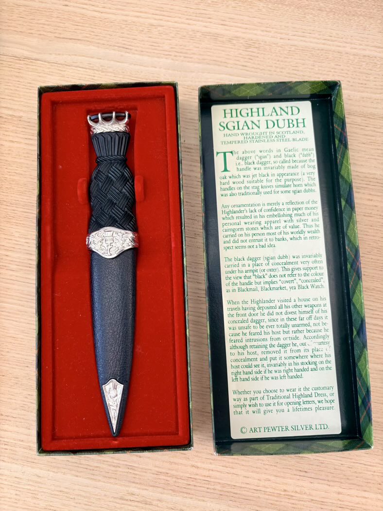 Sgian Dubh with silver top in red case and information card on wooden surface