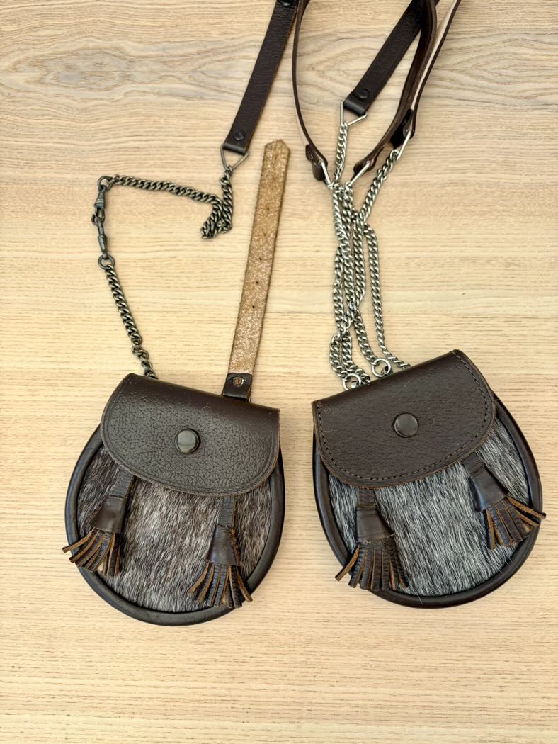 Two brown leather crossbody bags with fringe on a wooden surface, accompanied by a ruler for size reference.
