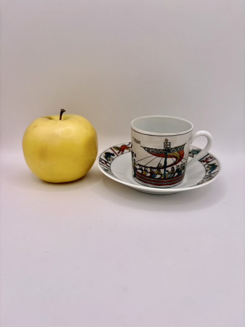 Ceramic cup with saucer and yellow apple on a white background