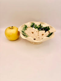 Decorative ceramic bowl with floral design next to a yellow apple on a white background