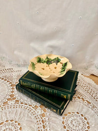 Decorative bowl on top of two stacked books with a lace tablecloth background