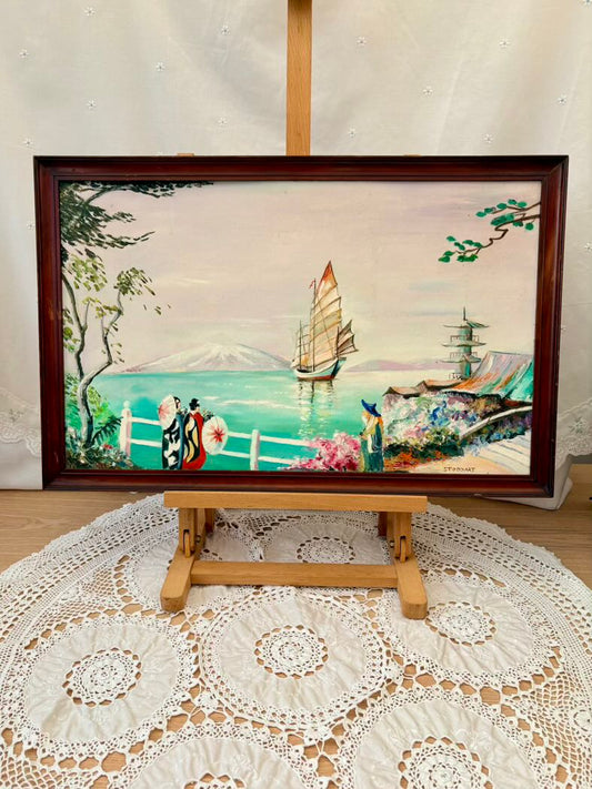 Framed artwork of a scenic landscape with a sailboat on a wooden easel.