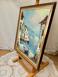 Framed painting of a coastal scene on a lace-covered surface