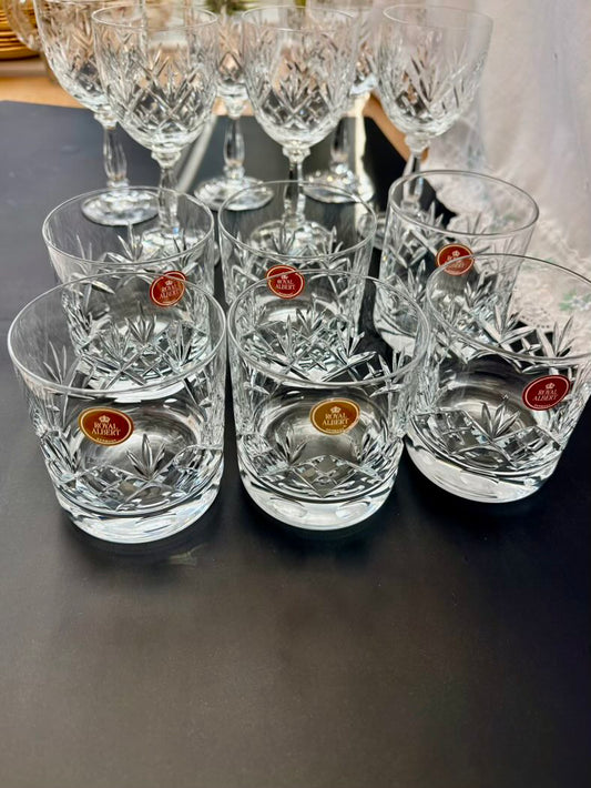 Set of crystal glasses with visible brand labels on a dark surface