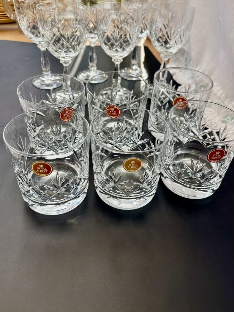 Set of crystal glasses with visible brand labels on a dark surface