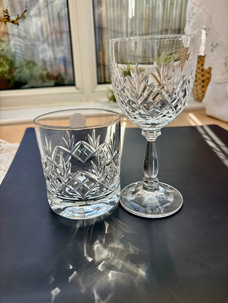 Two cut crystal glasses on a dark surface with a blurred indoor background