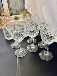 Set of crystal glasses on a reflective surface with blurred background