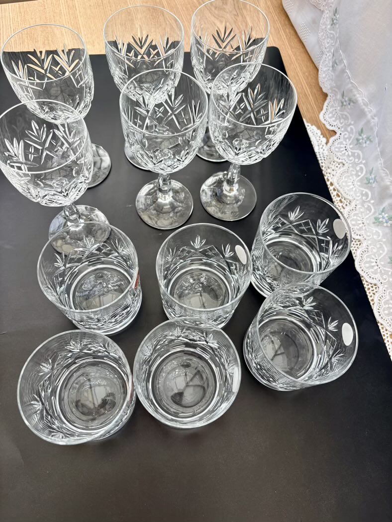 Set of crystal glasses with engraved designs on a dark surface.