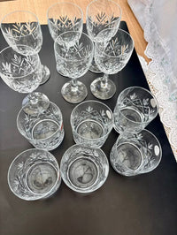 Set of crystal glasses with engraved designs on a dark surface.