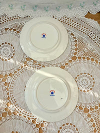 Two white plates with a logo on a lace tablecloth