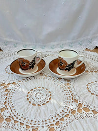 Two vintage-style teacups with saucers on a lace tablecloth.