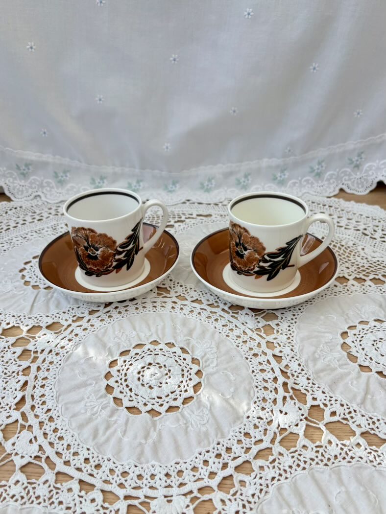 Two vintage-style teacups with saucers on a lace tablecloth.