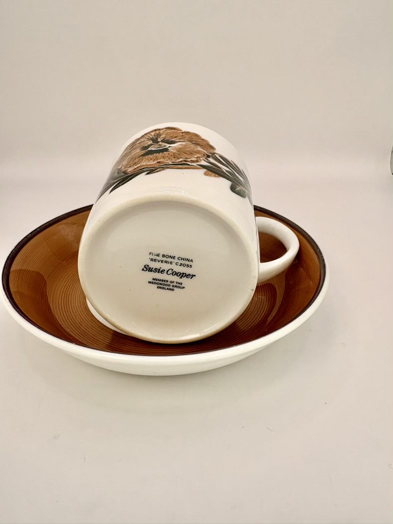 White mug with brown design on a matching brown saucer on a white background