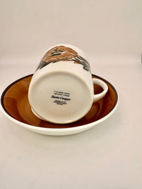 White mug with brown design on a matching brown saucer on a white background