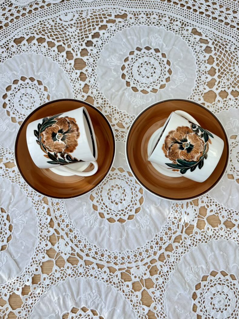 Two ceramic plates with floral designs on a lace tablecloth