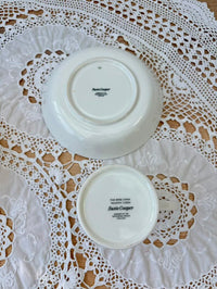 Two white plates with 'Saul Cooper' branding on a lace doily.