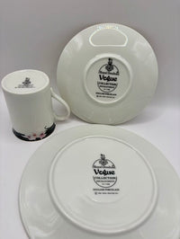 Ceramic mug and two plates with 'Vogue Collection' branding on a white background