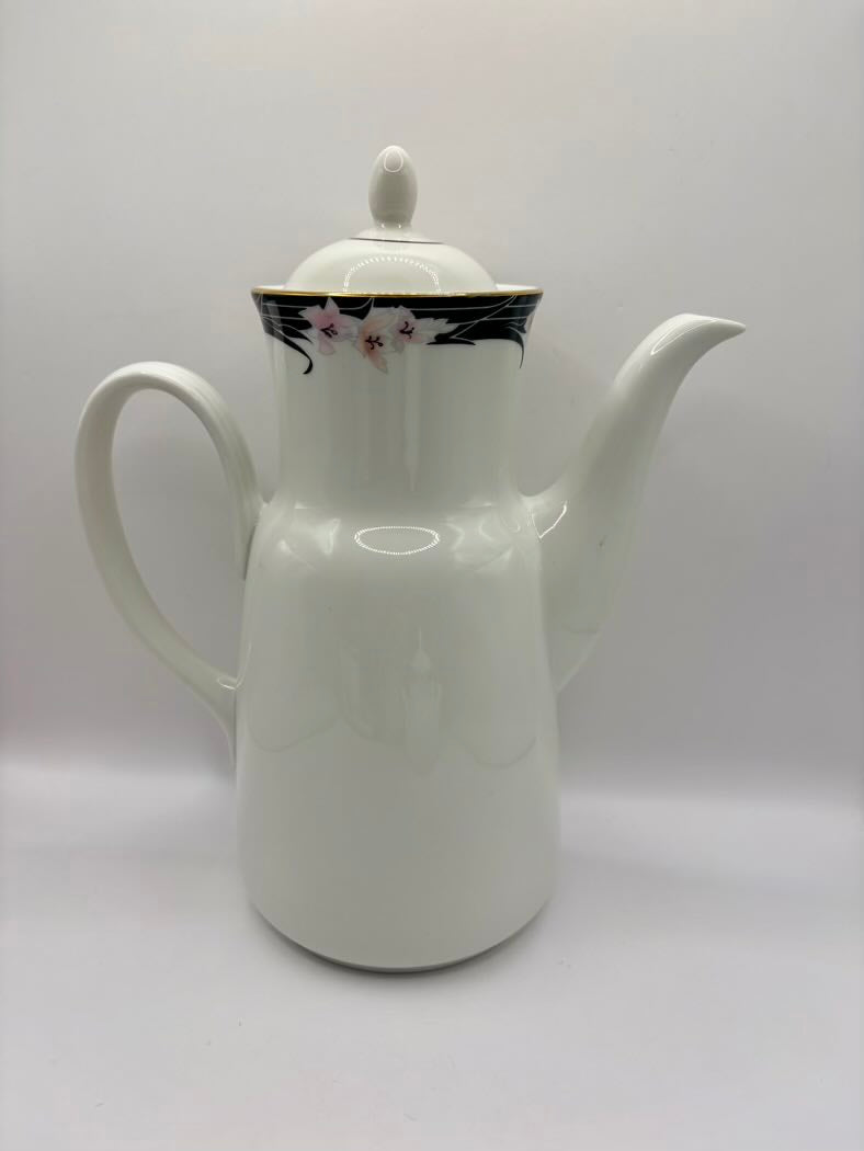 White ceramic teapot with floral design on lid against a white background