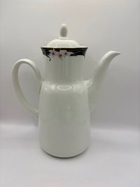 White ceramic teapot with floral design on lid against a white background
