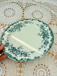 Decorative plate with floral pattern held over a lace tablecloth