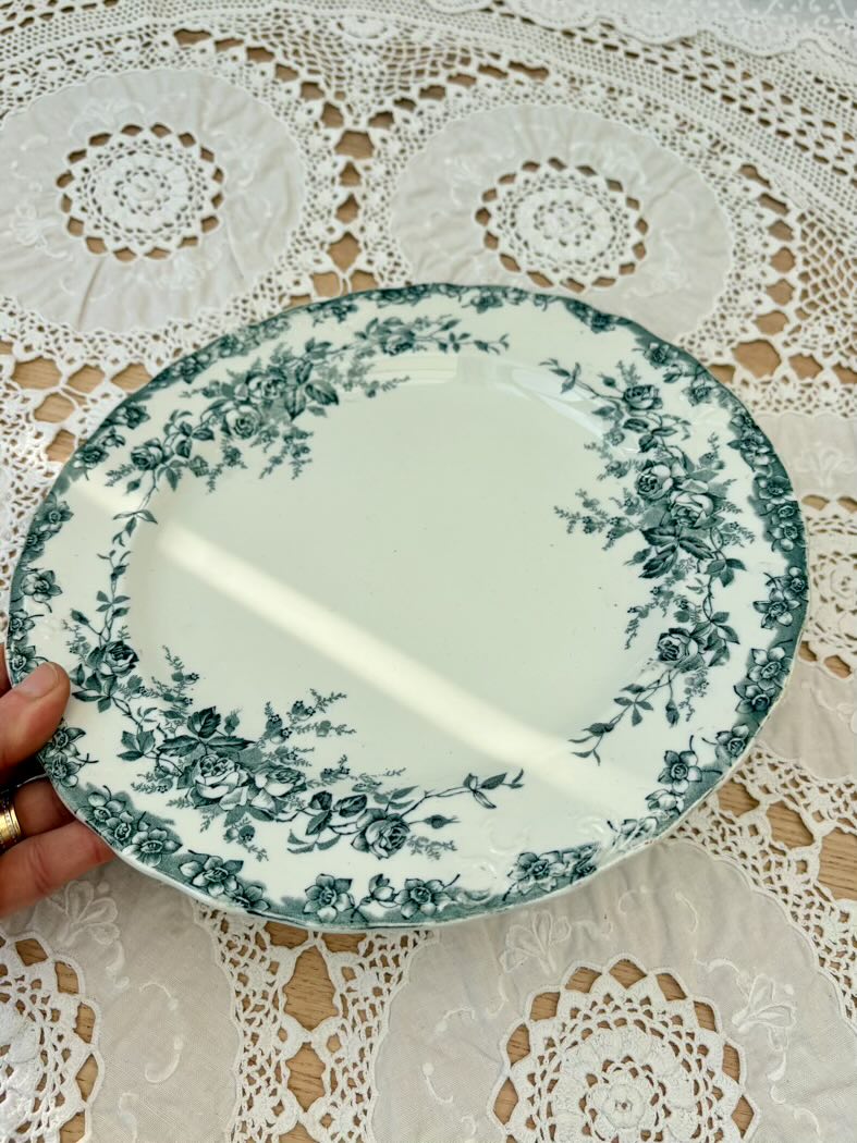 Decorative plate with floral pattern held over a lace tablecloth