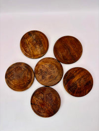 Set of six wooden coasters with engraved designs on a white background