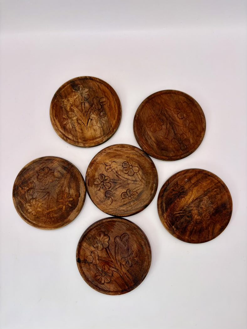 Set of six wooden coasters with engraved designs on a white background