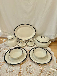 Set of ceramic dishes with black trim on a lace tablecloth
