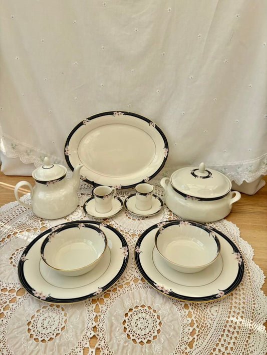 Set of ceramic dishes with black trim on a lace tablecloth