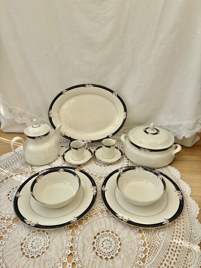 Set of ceramic dishes with black trim on a lace tablecloth
