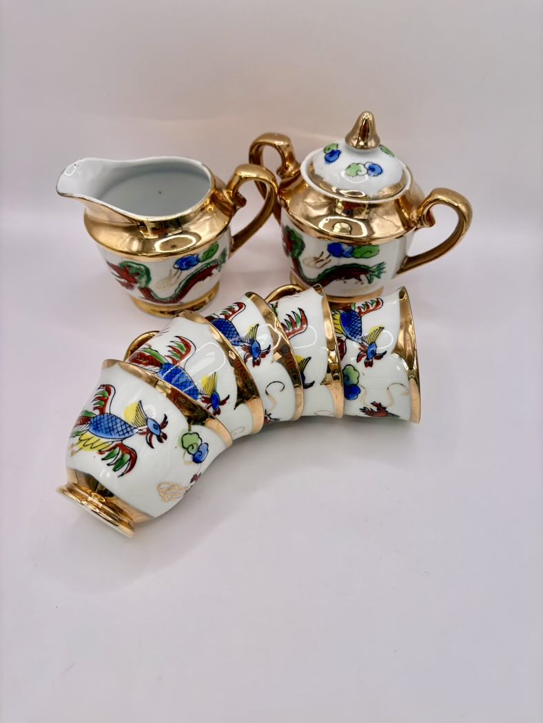 Decorative ceramic teapot, creamer, and sugar bowl set with floral patterns on a white background