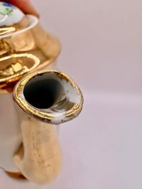Close-up of a ceramic teapot with gold trim on a plain background