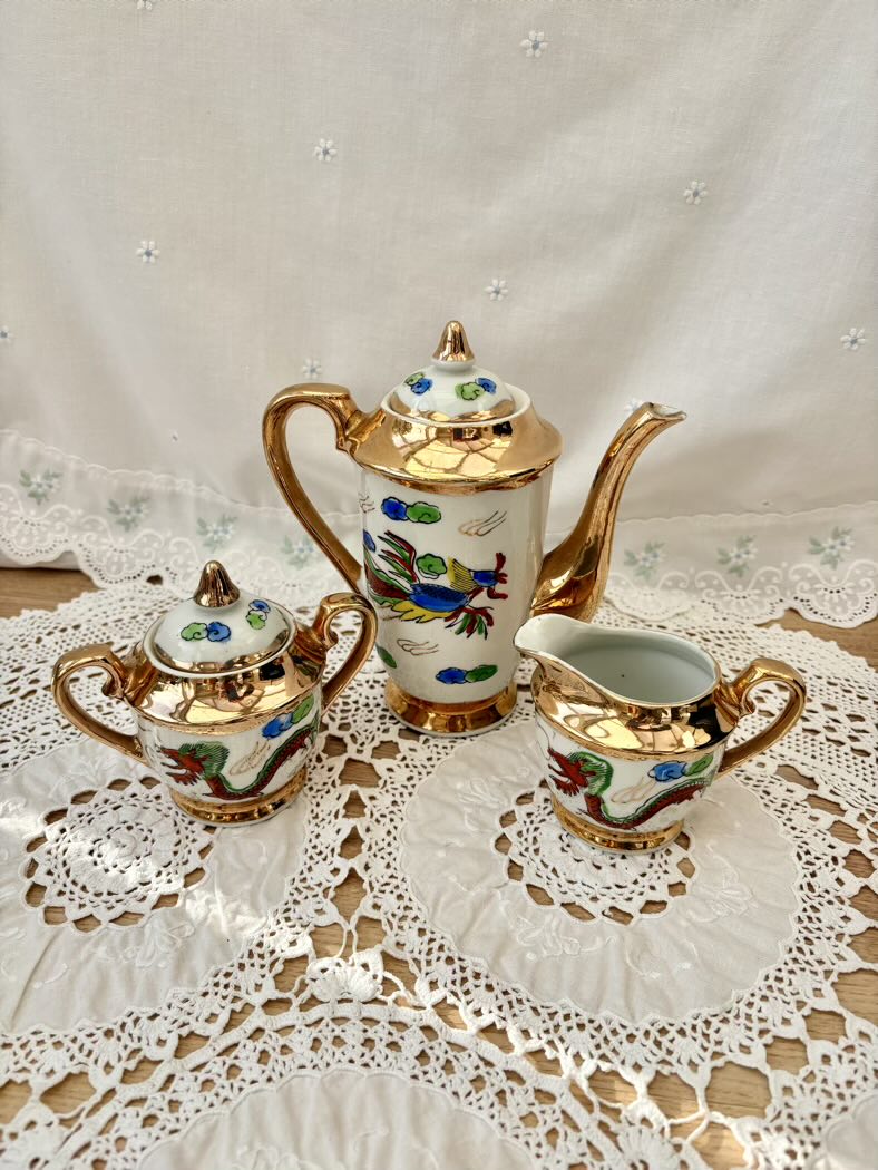 Decorative teapot, sugar bowl, and creamer set on a lace tablecloth