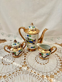 Decorative teapot, sugar bowl, and creamer set on a lace tablecloth