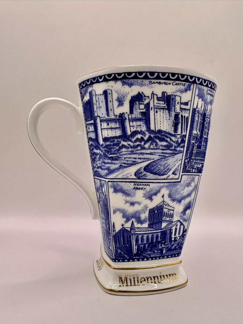 White ceramic mug with blue architectural illustrations and 'Millennium' text on a white background