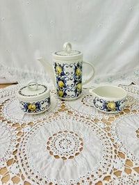 Ceramic tea set with decorative patterns on a lace tablecloth