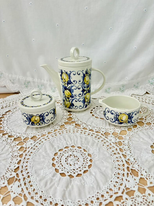 Ceramic tea set with decorative patterns on a lace tablecloth