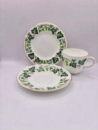 Tea set with cup and two saucers featuring green leaf patterns on a light gray background