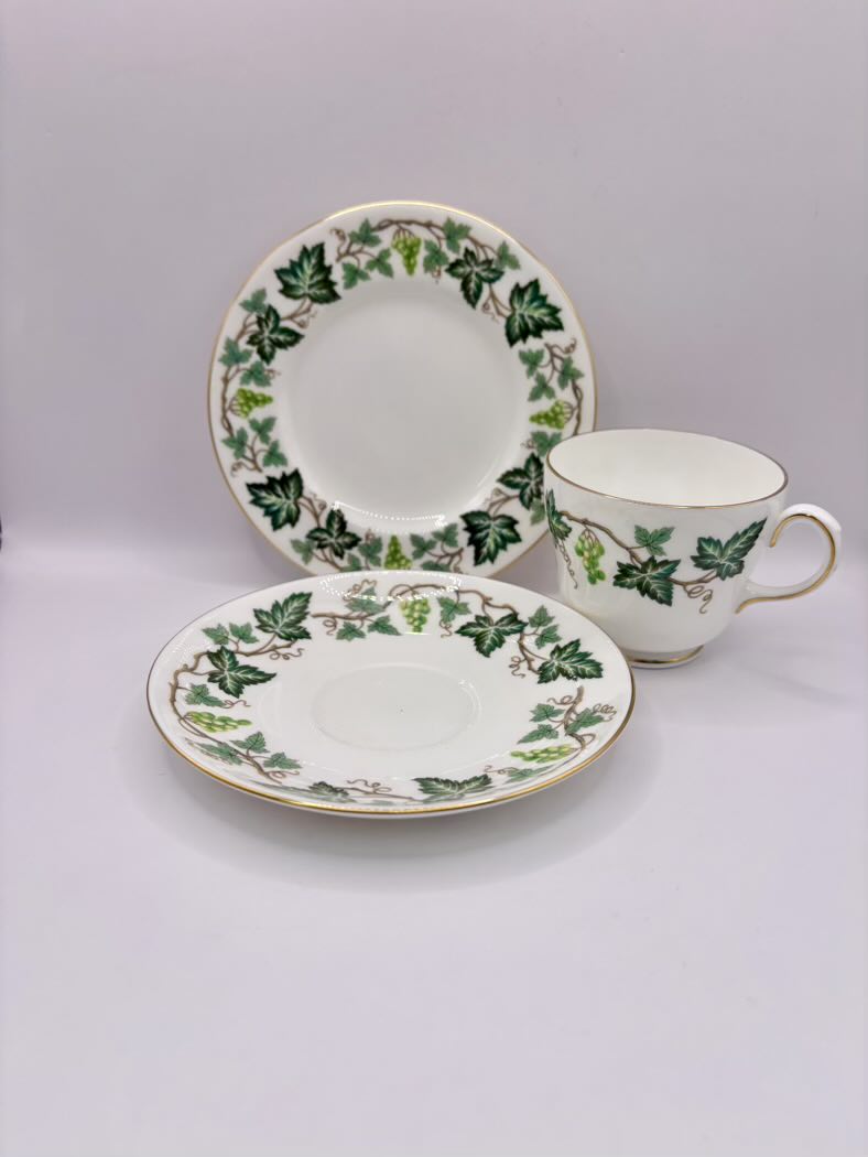 Tea set with cup and two saucers featuring green leaf patterns on a light gray background